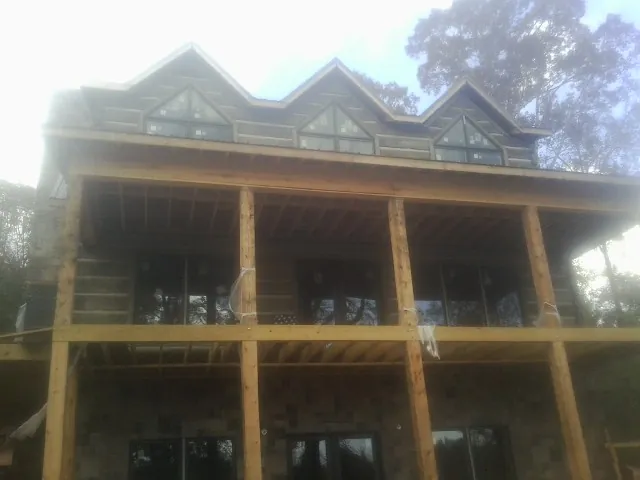 Dormers and porch framing on a large log home under construction — Roof Coating work by our crew in Reidsville