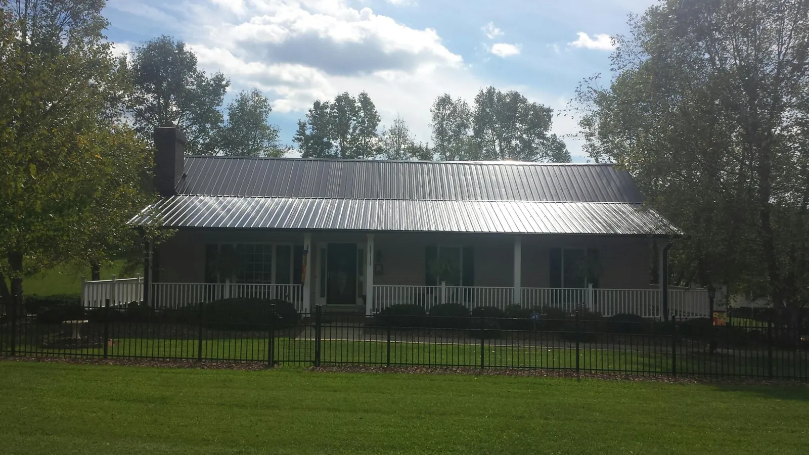 Gray metal roof on a brick ranch with a full width front porch — Gutter Guard Installation work by our crew in Reidsville