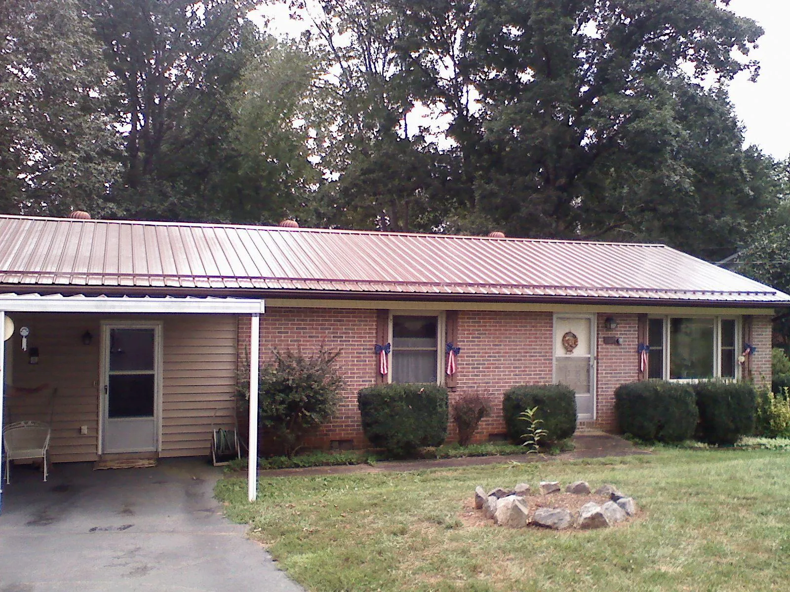 Bronze metal roof and carport on a brick ranch home — Roof Repair work by our crew in Reidsville