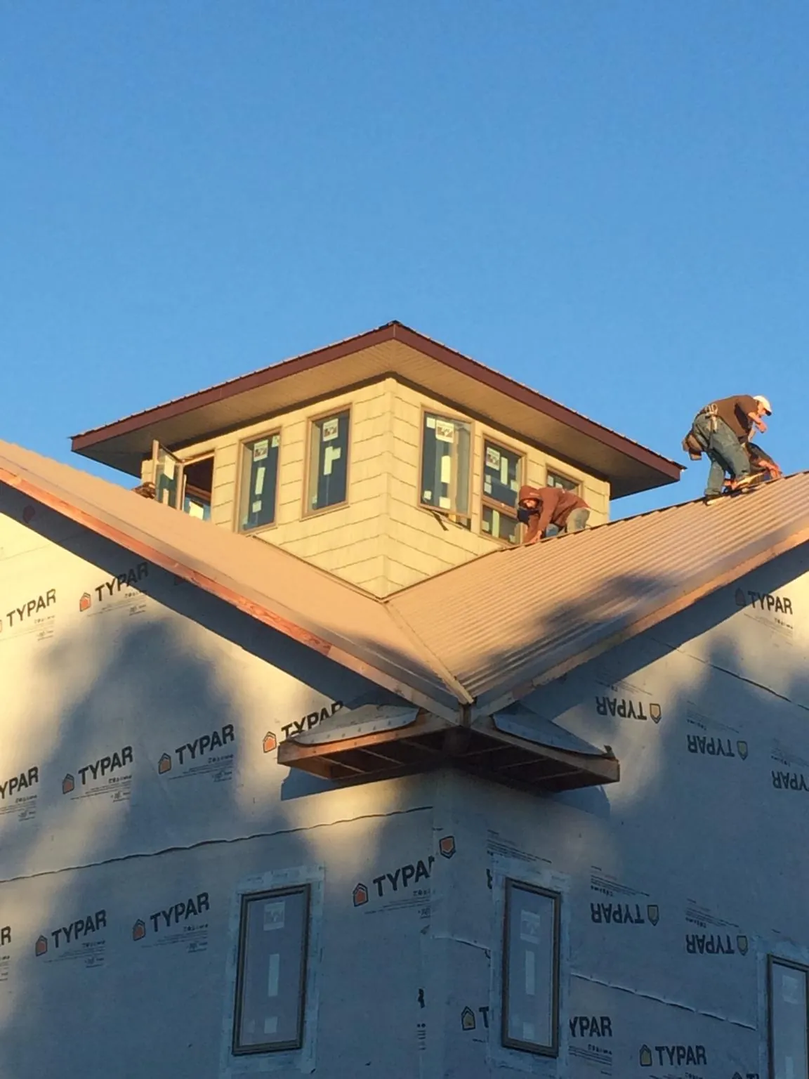 Roofers working around a rooftop cupola on a new metal roof at sunset — Roof Waterproofing in Reidsville by Roofing Brothers